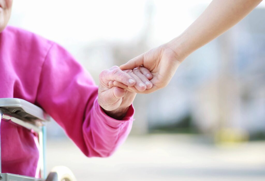 A person holding another persons hand while standing on the street.