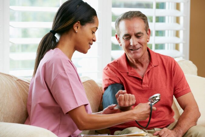 A nurse checking the blood pressure of an older man.